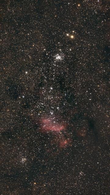 Faint pink nebulosity amongst a scattering of little star clusters.