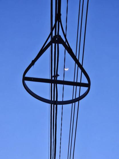 Dark black power lines with an unusually shaped resistor against the dark blue night sky.