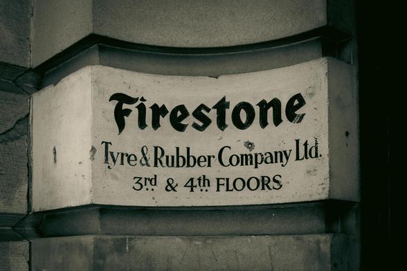Curved stone with text: "Firestone | Tyre & Rubber Company Ltd. | 3rd & 4th Floors".