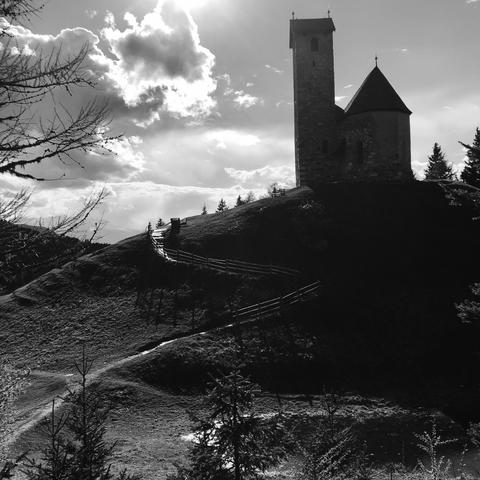 Una chiesa sulla cima di una collina ed un sentiero che sale sulla collina con uno steccato al suo lato