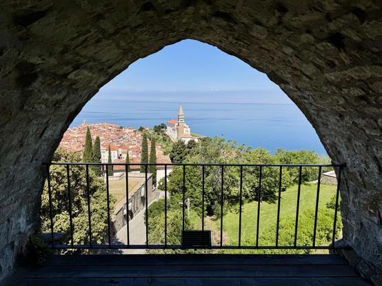 View from with archway in fortified tower of Piran Town Walls, looking towards the town below including bell tower