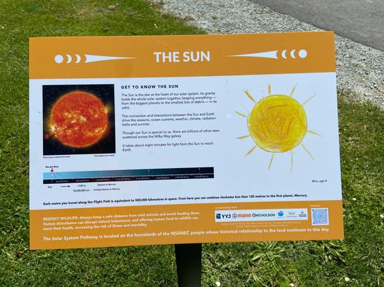 The sun's plaque at the starting point of the model of the solar system. A photo of the sun showing sunspots, flares, and granules, the distance scale, and a charming child's drawing.