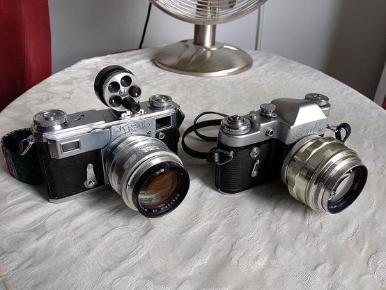 Two Soviet cameras on the table - on the left a Kiev 4A with a 85mm Jupiter-9 lens (Kiev mount, made by Arsenal, or possibly KMZ), on the right a Zenit 3M with a different 85mm Jupiter-9 lens (m39/Zenit mount, made by LZOS)