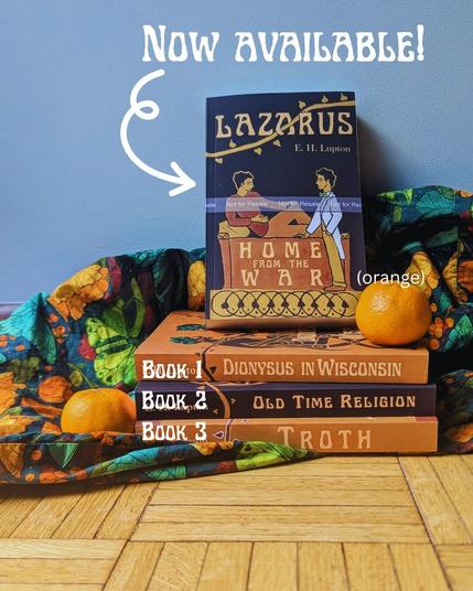 A stack of books in front of a green and orange, somewhat floral fabric. There's an orange next to the books and an orange on the top of the stack. The book facing us is Lazarus, Home from the War, and it's sitting on Dionysus in Wisconsin (labeled "book 1"), Old Time Religion  ("book 2"), and Troth ("book 3"). The words "Now Available!" have an arrow pointing to the Lazarus book.