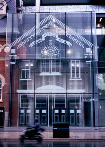 A glass false front covers the facade of a condo tower, on it is etched the outline of the facade of the firehouse that once stood here, better known later as the St. Charles Street Tavern.