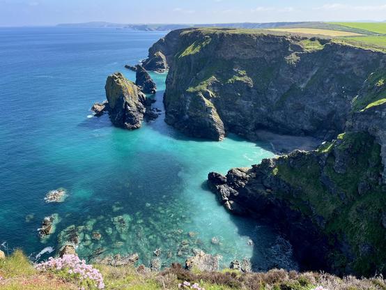A dramatic cliff top view looking over blue waters peppered with rocks.