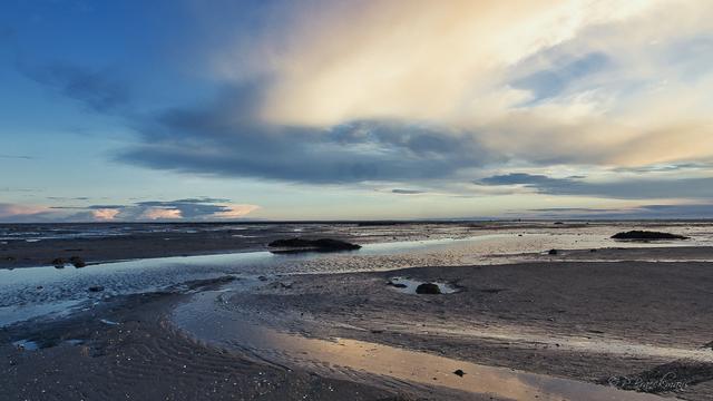 Foto van een zonsondergang aan de Opaalkust in Frankrijk genomen. Een geul met terugtrekkend water zorgt voor de invoerende lijn.