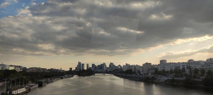 Le soir tombe sur la Seine , le ciel encore bleu caché par un énorme nuage gris, au loin la défense