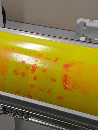 A yellow color drum from a riso printer with red residue from the past print job.