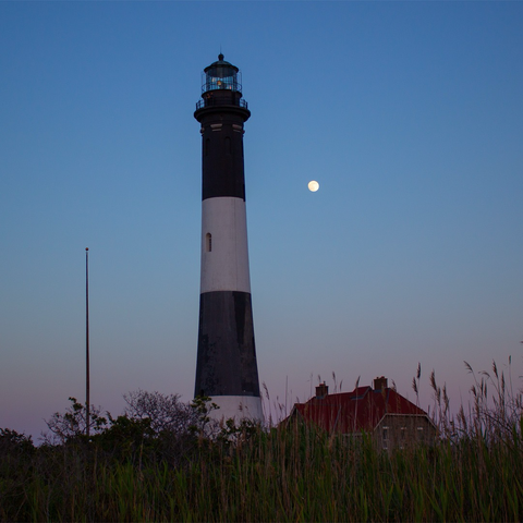 Image of a lighthouse at dusk with a full moon behind it