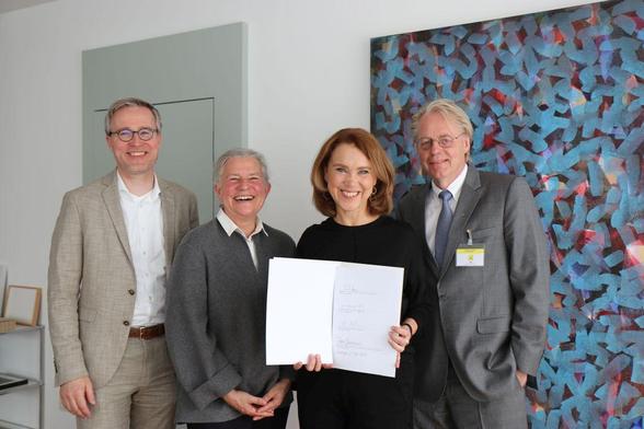 Gruppenbild nach der Unterzeichnung (von links): Professor Peter Middendorf, Rektor der Universität Stuttgart, Professorin Karla Pollmann, Rektorin der Universität Tübingen, Wissenschaftsministerin Petra Olschowski, die das Memorandum of Understanding in die Kamera hält, und Professor Jan S. Hesthaven, Präsident des KIT.