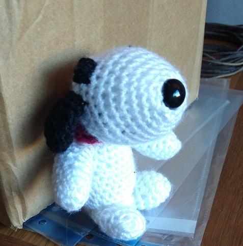 Side view of a crochet snoopy with black nose, ears and eyes