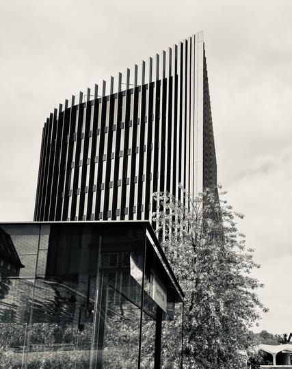 View from a tram window of a super modern building which looks like thin vertical lines with a slightly curved profile