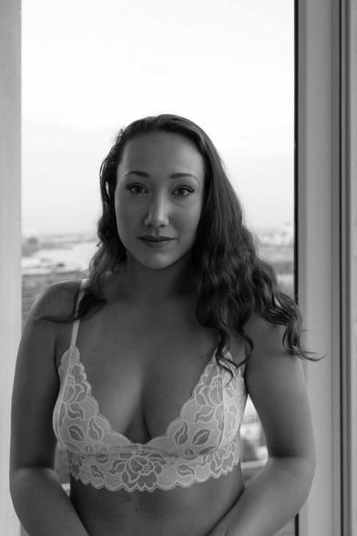 A portrait of a feminine woman in a lacy flower print bra staring calmly.