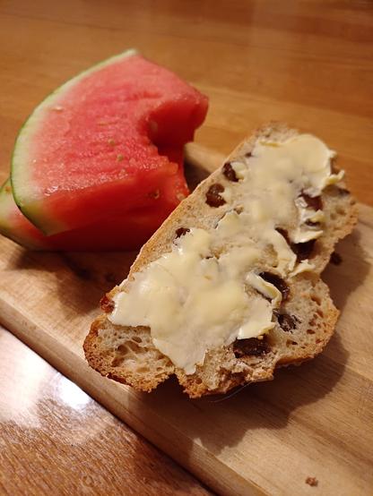 Ein Rosinenbrot mit Butter, zwei Stück Wassermelone.