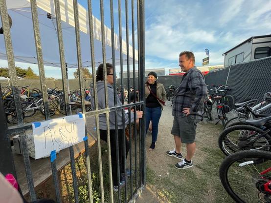 Inside the valet station packed with bicycles, and skateboards, the bike valet attendant is chatting with two Cali Roots 2022 attendees.