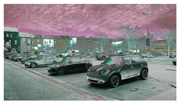 Colour adjusted photograph showing an inner city car park under a purple sky.