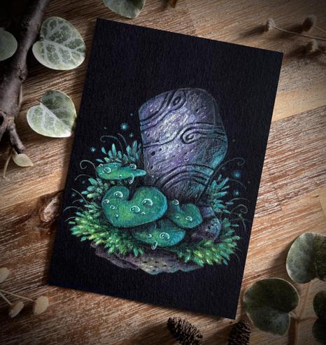 A photo of a painting on black paper, placed on a wooden table and surrounded by branches, dried flowers, and leaves for decoration. The painting features a standing stone with curving lines carved on its surface. Big leaves with dew drops on them and grass grow at its base.