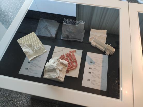 Eine Ausstellung von mehreren, ca. 10x10cm grossen, 3D-gedruckten Kartenausschnitten von Bergen, Gebäuden und Städten.