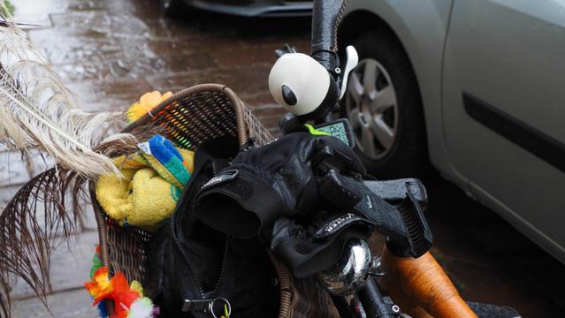 Gelbes Handtuch im Fahrradlenkerkorb. Im Hintergrund sieht man feuchten Bürgersteig