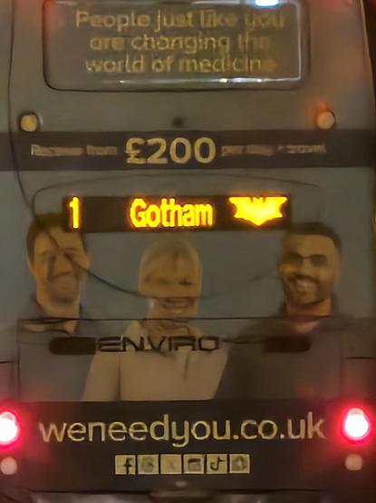 Photo of the back of a bus. The sign says "1 Gotham" followed by an illuminated Batman Symbol