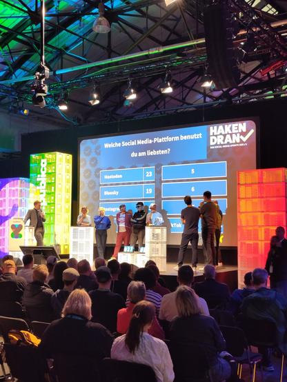 Menschen in zwei Teams auf einer Bühne bei der re:publica, dahinter sind die Antworten auf die Frage eingeblendet "Welche Social Media-Plattform benutzt du am liebsten?"