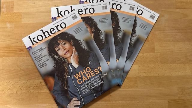 Vier Exemplarte der gleichen Ausagbe des Magazins kohero liegen auf einem Holztisch. Auf dem Cover steht in großen Buchstaben „WHO CARES?“. Das Titelthema der Ausgabe beschäftigt sich mit Care-Arbeit, Gleichberechtigung und Fürsorge. Auf dem Titel ist eine Frau mit lockigen Haaren abgebildet. © Hussam Al Zaher