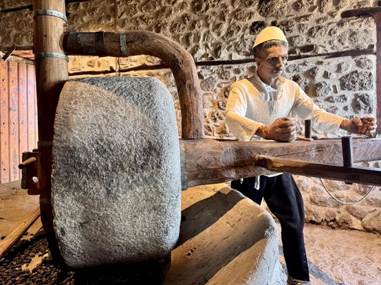 Manikin operates a stone olive press