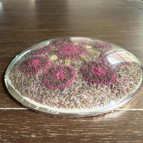 A side view of a convex frameless picture frame over a pink and purple abstract flower. The unevenness of the silver tape keeping the glass and back together is evident; I need to re do it or, better yet, get my patient husband to do it.