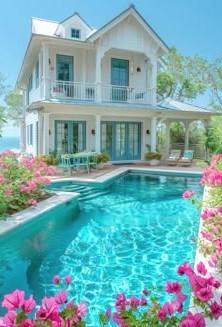 Beautiful small white Victorian house with a refreshing pool and pink flowers surrounding the pool