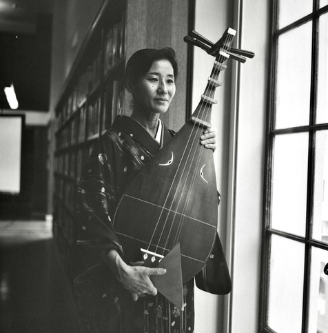 A black and white film photo. Nobuko is holding her Biwa after a performance at the Central Library in Los Angeles, California. Saturday, May 17, 2025.