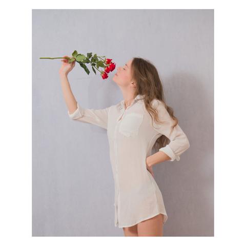Female model smelling the aroma of a bunch of red roses