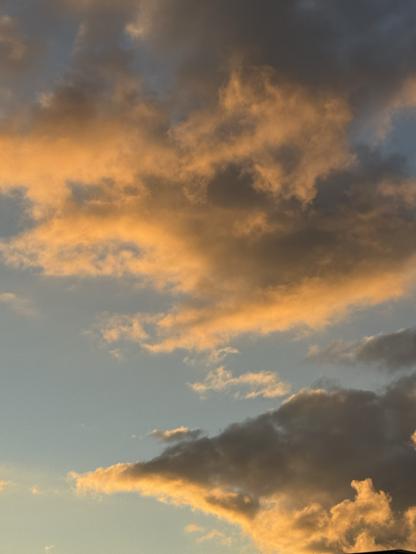 Von der Abendsonne beleuchtete Wolken vor blassblauem Himmel