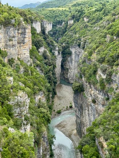 View of gorge with vegetation on cliffs to either side; gravel banks visible either side of turquoise river
