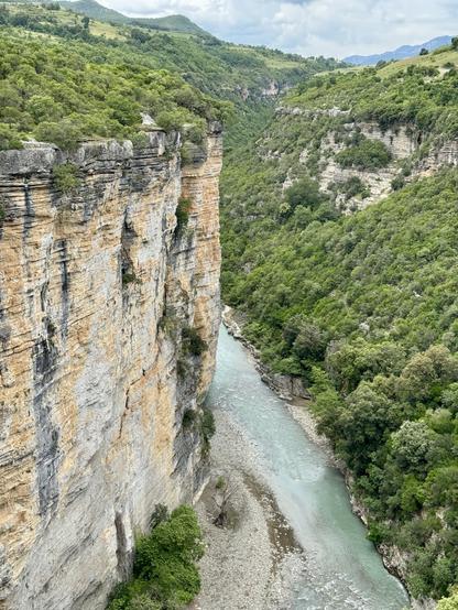 Sheer bare cliffs left of frame; the right bank is sloping & clad in vegetation