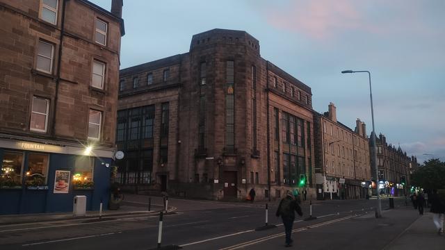 Mid 20th century architecture of Fountainbridge Library, with the distinctive tower on the corner, catching the last, red rays of the setting sun