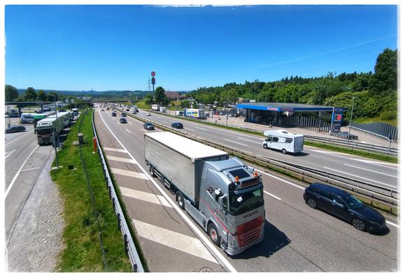 Picture taken on a bridge crossing a motorway with 6 lanes. Some cars and trucks passing.