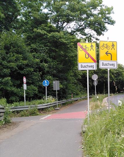 Am Rand des Weges stehen zwei widersprüchliche Umleitungsschilder.