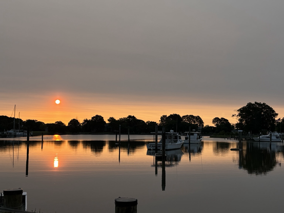Hazy sunrise over the water with workboats docked.
