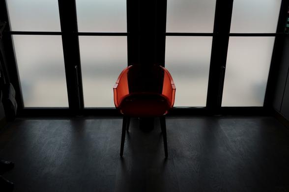 A transparent red chair in front of a window