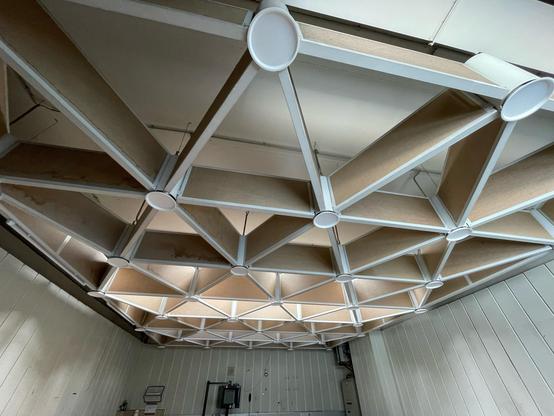 Foto einer Akustikdecke mit sternförmig angeordneten Modulen. Die einzelnen Paneele sind ca 100x40cm, die runden Verbindungsstücke ca 20cm im Durchmesser.