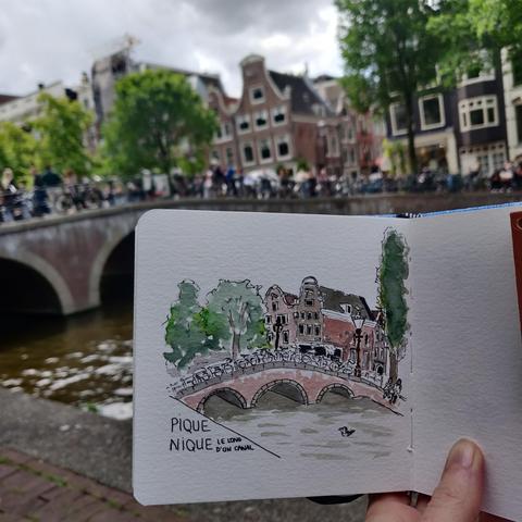 Photo de mon carnet avec l'aquarelle du pont, prise devant le paysage dessiné