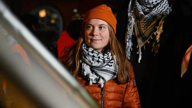 Photo of Greta Thumberg wearing orange jacket and winter hat, and a Palestinian keffiyeh.