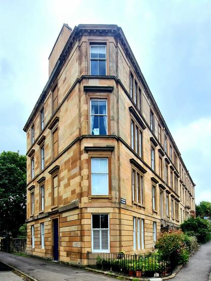 A blonde sandstone corner tenement in Glasgow.