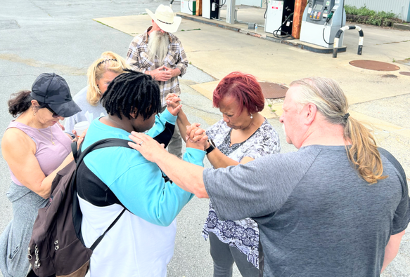 People gathered together randomly to pray together outside a gas station