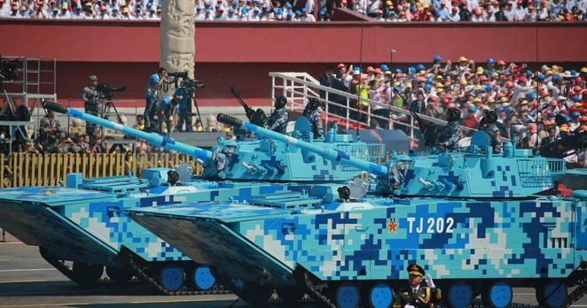 Zwei Panzer bei einer Militärparade, die nicht wie üblich grün, sondern in einem blauen Tarnmuster angestrichen sind.