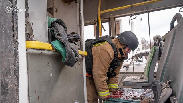 Ein ukrainischer Helfer arbeitet in einem Bus, der von russischen Angriffen zerstört wurde. Der Innenraum des Busses ist völlig demoliert. 