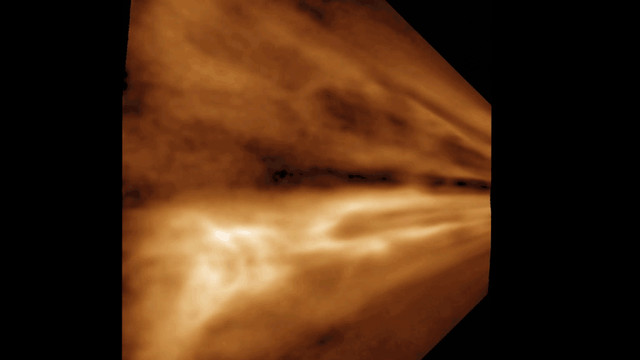 A data visualization shows columns of glowing, golden-brown clouds streaming across the screen. The motion creates the illusion of flying through a tunnel of swirling plasma, with brighter, denser regions pulsing and twisting to suggest turbulence and varying intensity. Warm tones of amber and bronze contrast against a deep black background, enhancing the sense of depth and motion as the clouds flow dynamically from right to left, capturing the energetic and storm-like behavior of the Sun’s outflowing atmosphere.