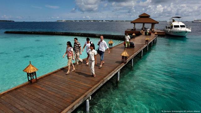 Tourists walking along a wharf in the Maldives