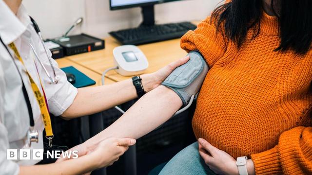 A pregnant woman having her blood pressure checked by a doctor